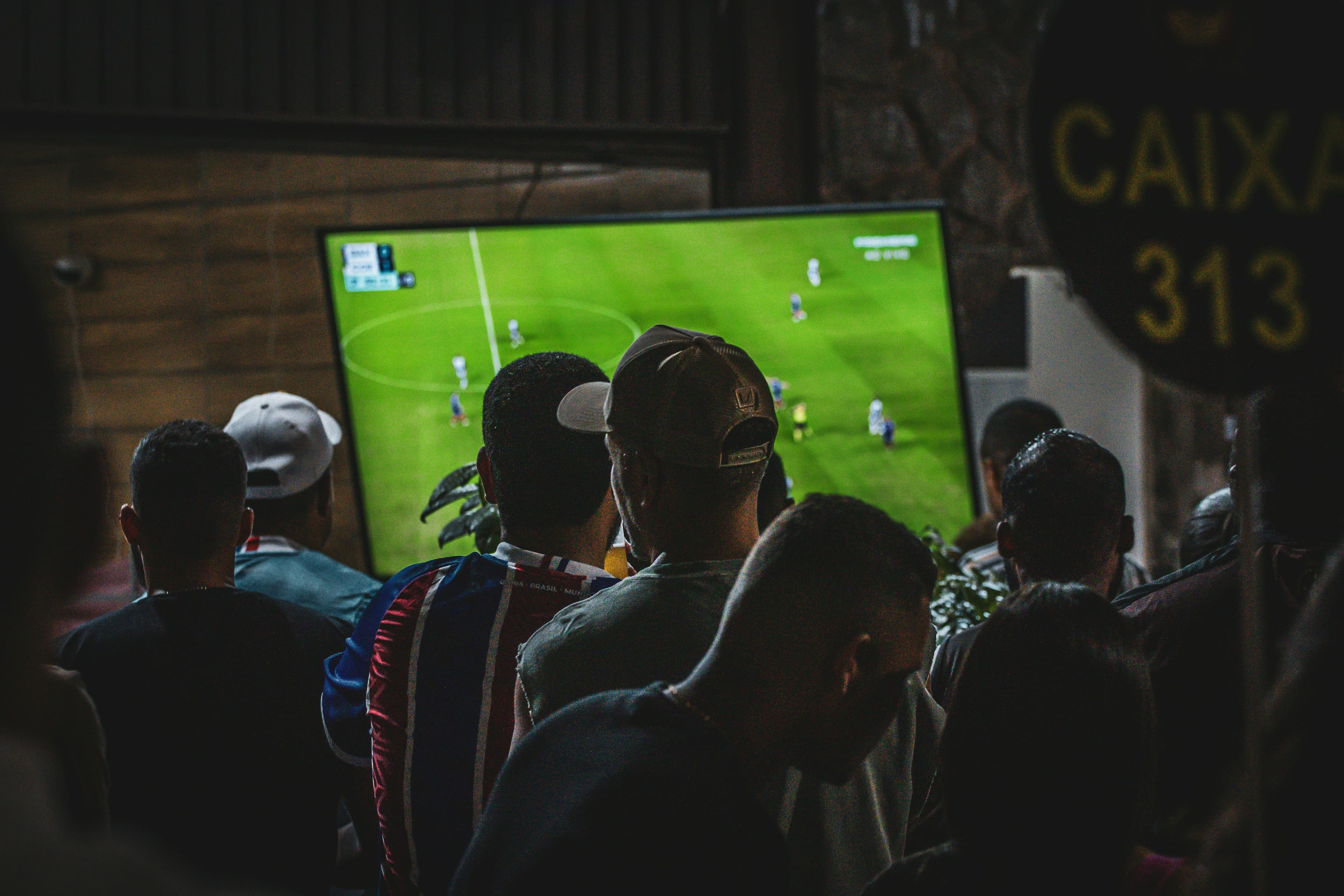 Deux amis assis sur un canapé, concentrés sur un match de football à la télévision.